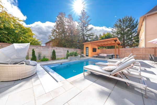 Finished fiberglass pool with interlock patio and surrounding landscaping